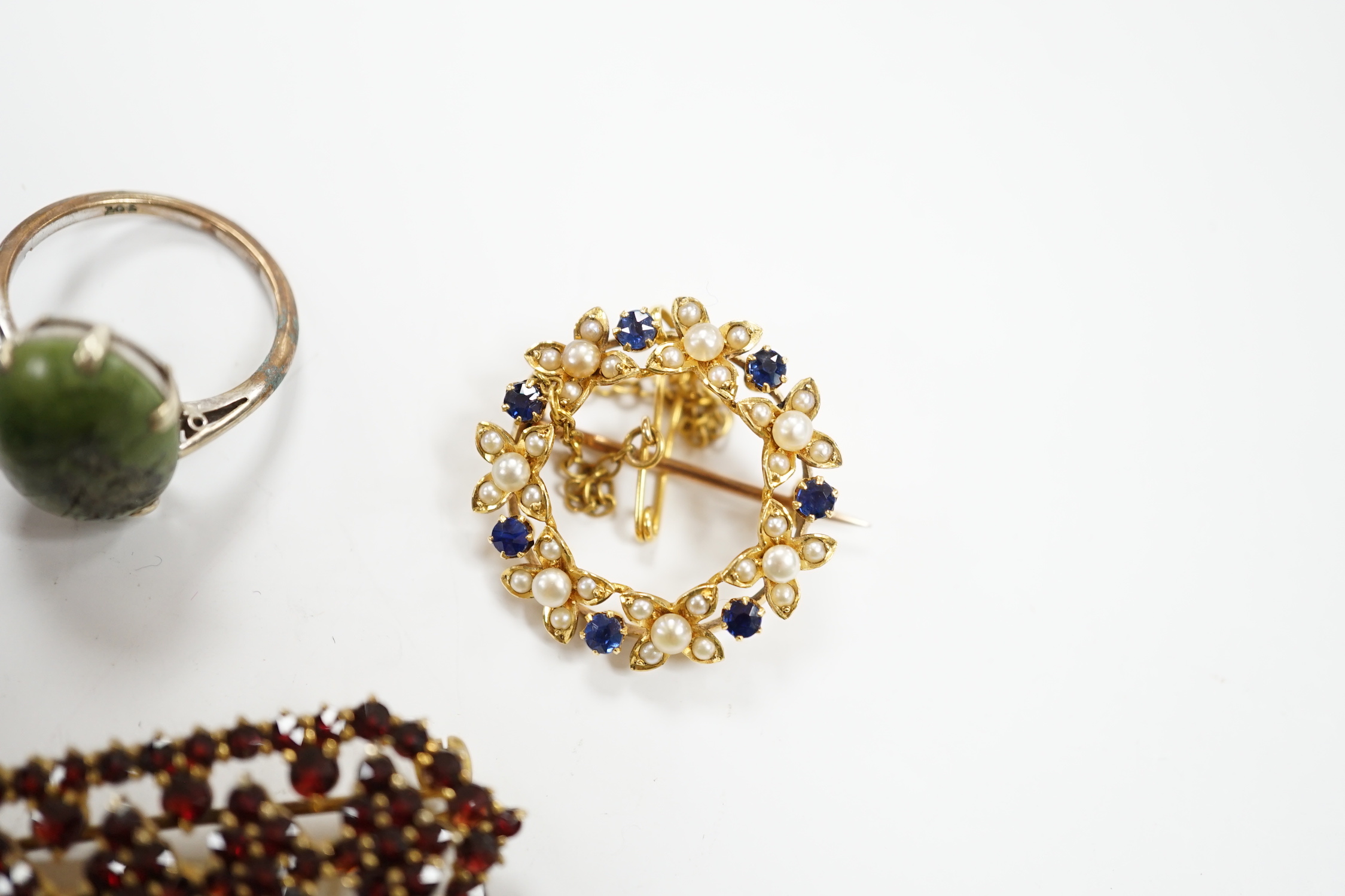 A yellow metal, sapphire and seed pearl cluster set openwork brooch, 23mm, a 9ct and hardstone ring, four items of garnet set jewellery and a pair of jade set ear studs.